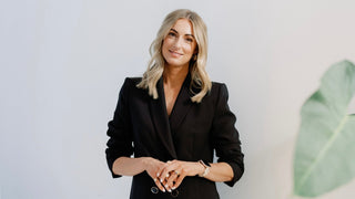 Sophie Doyle wearing a black blazer with hands at waist smiling toward the camera