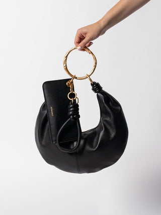 #colour_black-gold,Harriet Case pictured with the Dumpling Handbag, Grande Ripple Carabiner & Knot Key Ring in Pebbled Leather.